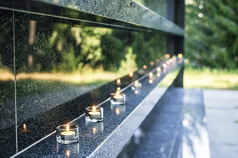 Kolumbariumo nišos su uždegtomis memorialinėmis žvakutėmis lauko erdvėje