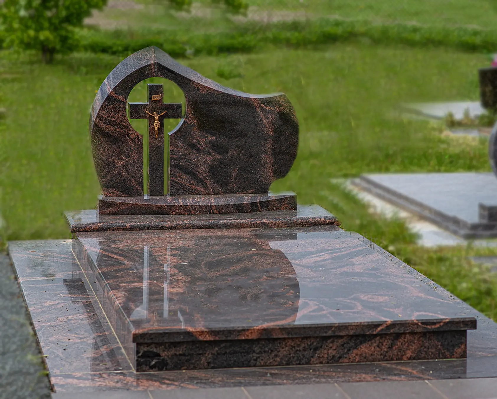 Juodo granito kapavietės paminklas su auksiniu kryžiumi ir baltų gėlių kompozicija