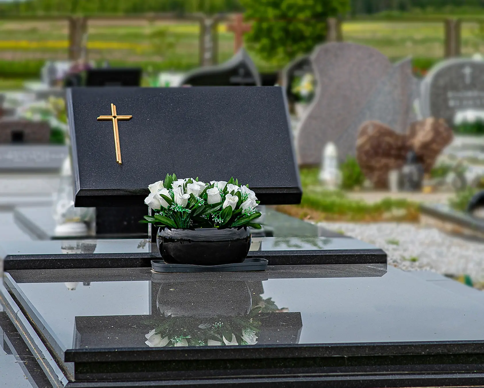 Tamsaus granito paminklas su banguotos formos antkapiu ir poliruota kapavietės danga